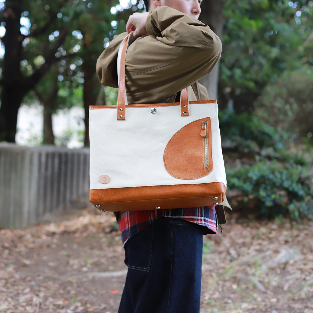 トートバッグ DUOトートver2 ｜ 帆布 牛革 キャメル×オフホワイト 使用イメージ 側面 男性 公園
