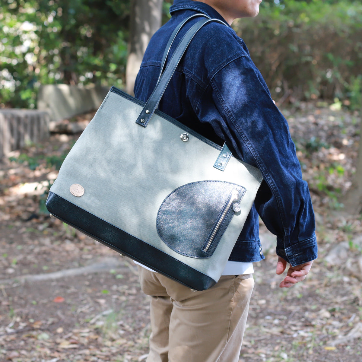 トートバッグ DUOトートver2 ｜ 帆布 牛革 ネイビー×グレー 使用イメージ 男性 側面 公園
